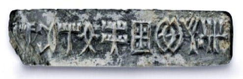 Stone seal fragment with Indus script from the Saraswati–Sindhu (Indus Valley) Civilization, showing a short inscription on a rectangular grey tablet, likely used for civic or trade administration.