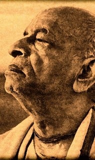 Sepia-toned profile of an elderly person, eyes closed and head uplifted, in simple robes and bead necklace—evoking calm reflection for an A.C.B. Swami Prabhupada article on others’ welfare.