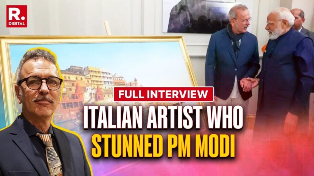 A suited man stands by a framed riverside cityscape as an Indian dignitary shakes hands with another man beside the artwork; on-screen text reads 'Full Interview: Italian artist who stunned PM Modi'.
