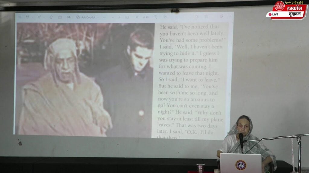 A speaker presents a slide with a vintage photo and English text during a live ISKCON Vrindavan session on Srila Prabhupada Lilamrita, in a classroom setting; accessible, testing category.