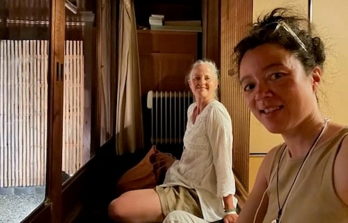 Two women sitting inside a traditional Kyoto machiya with wooden screens, illustrating guru yoga, Dharma tradition, and finding a spiritual mentor.