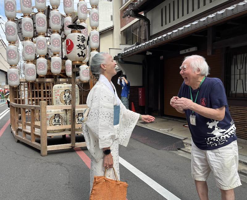 Catherine Sensei laughs with a Kyoto community member beside Gion Matsuri Festival lanterns, reflecting guru yoga, Dharma tradition, and spiritual mentor practice.