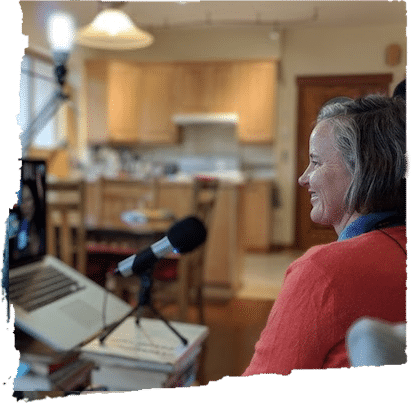Woman in a red sweater beside a laptop and microphone, reflecting modern day guru yoga, Dharma practice, and learning with a Spiritual Mentor.