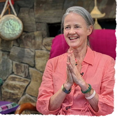 Smiling female Dharma teacher in salmon shirt with hands in prayer, reflecting guru yoga, Awakening and finding a spiritual mentor.