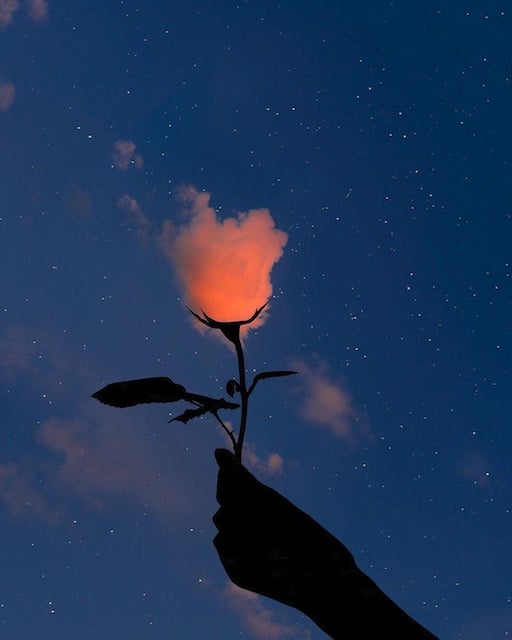 Silhouetted hand holding a rose with a glowing cloudlike bloom under a starry sky, symbolizing tantra, desire, Awakening, community, and The Path