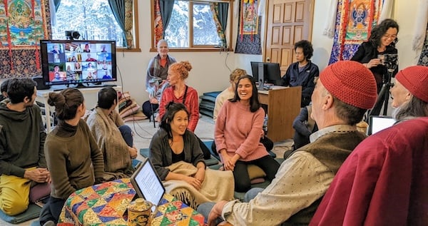 Dharma community seated in a circle with online participants on a screen, reflecting Integral Evolution and 21st-Century Awakening practice.