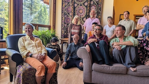 Dharma teacher seated with a smiling retreat community, reflecting Integral Evolution, sangha, and 21st-Century Awakening.