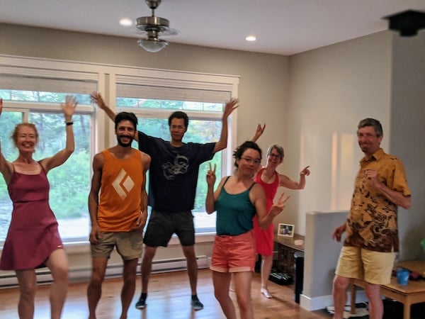 Six adults dance and wave in a bright retreat room, showing Dharma community joy in Integral Evolution and 21st-Century Awakening.