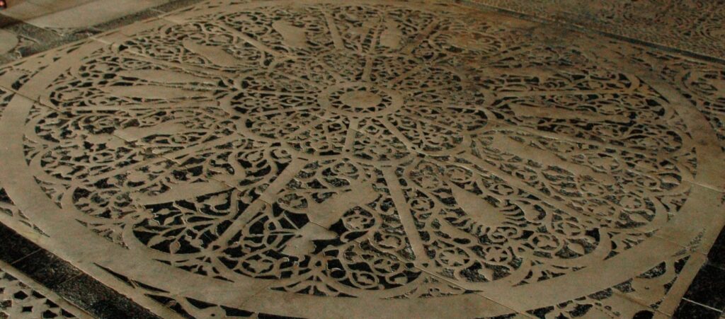 Angled view of a historic stone zodiac floor with carved astrological symbols, used for Astro-Dharma reflection on Saturn and mastery.