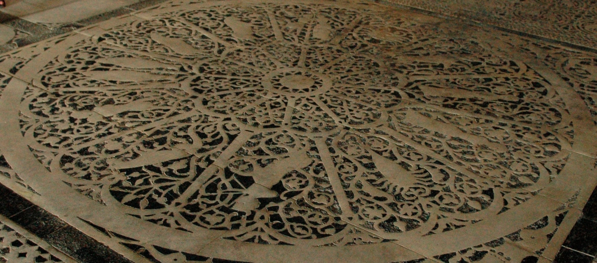 Angled view of a historic stone zodiac floor with carved astrological symbols, used for Astro-Dharma reflection on Saturn and mastery.