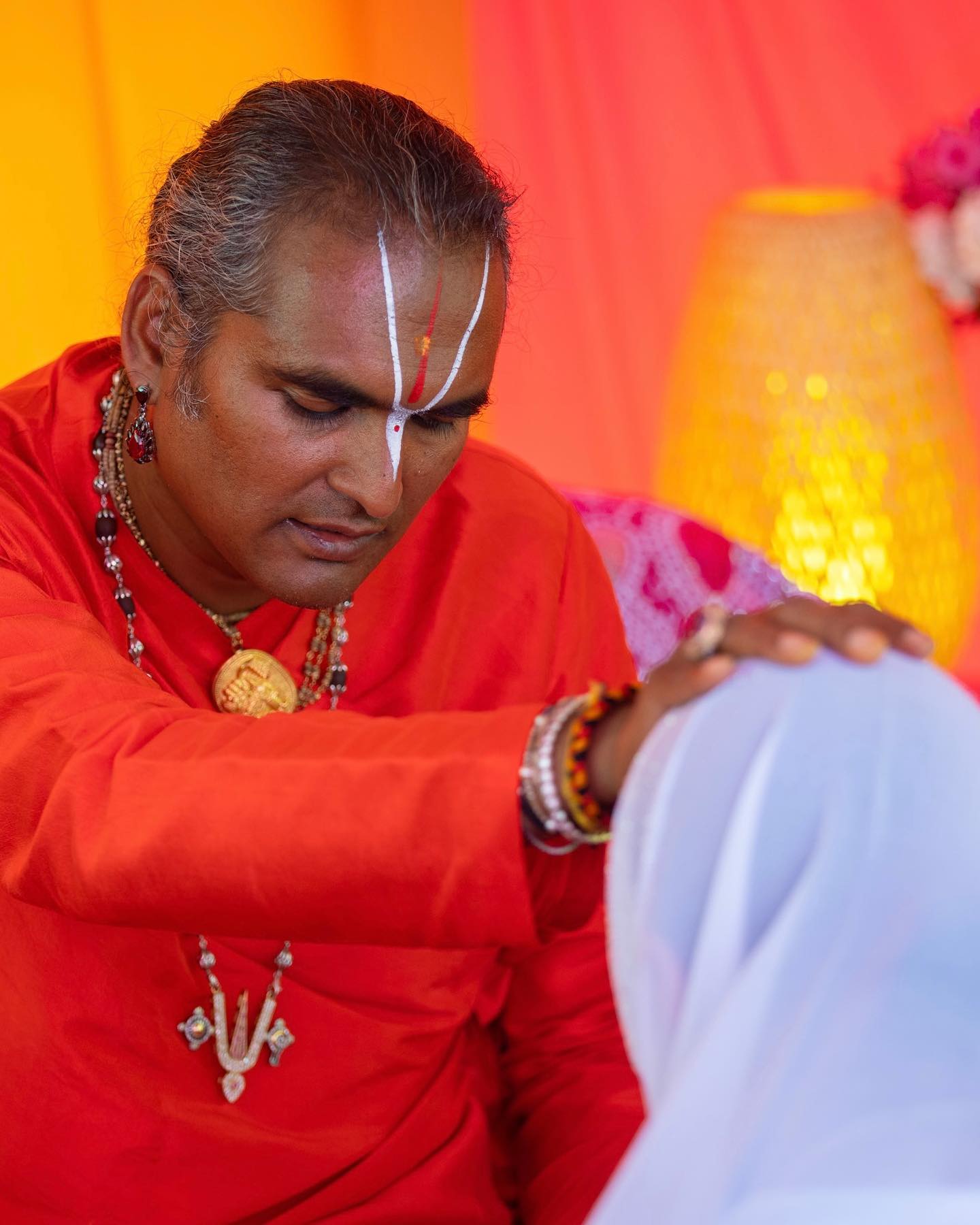 Hindu spiritual guide in red robes blessing a bowed devotee, illustrating a lifestyle of devotion, prayer, and the soul’s longing.