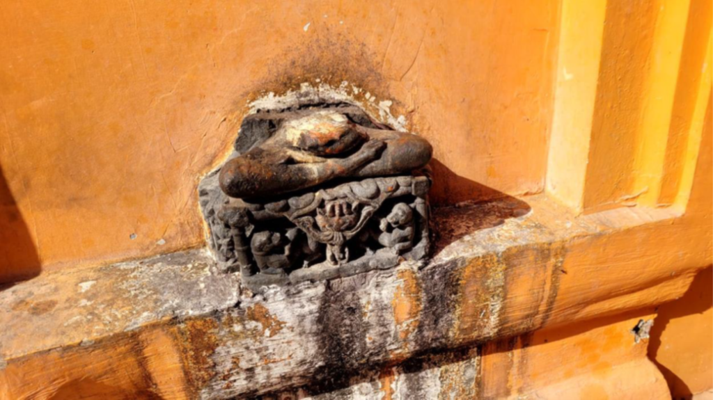 Eroded stone idol set into an orange wall at Prithvinath Temple, showing weathering and ritual staining in a TEMPLE TRAIL view of hindu temples.