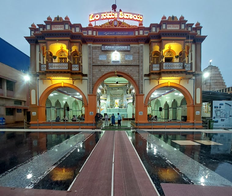 Rain-washed entrance of Siddharoodha Swami Math in Hubballi, lit for evening worship during a Karnataka dharma pilgrimage