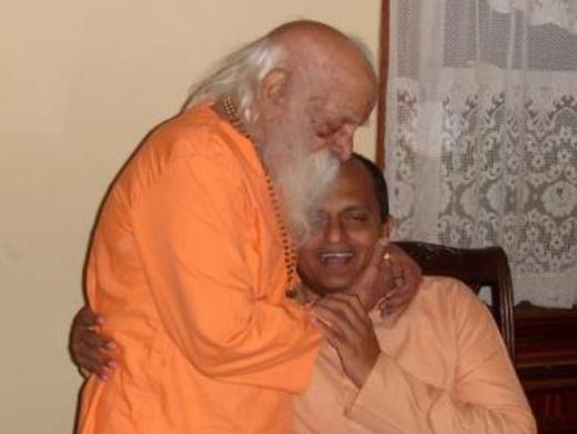 Swami Bua ji embraces Yogi Dileep Kumar in saffron robes, a Kerala yoga guru linked to United Nations Yoga Day and Sanatana Dharma conversations.
