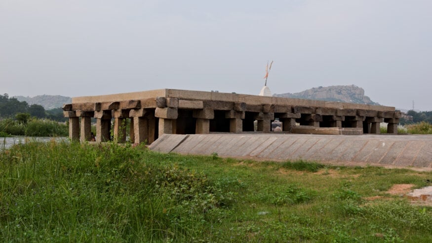 Purandaradasa Mantapa at Hampi, Bharat, with stone pillars and green banks, linking Hindu Dharma, Haridasa bhakti and Carnatic music tradition.