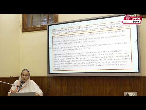 HG Daivi Shakti Mataji speaks at a microphone beside a projected slide during Srila Prabhupada Lilamrita class, dated 28.06.2026.
