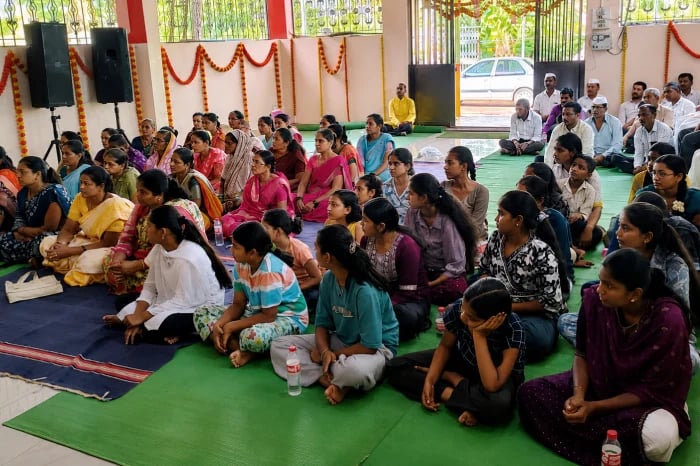 Residents seated on floor mats at a community meeting in Bisur, Sangli, as Hindu families discuss safety concerns amid alleged harassment.