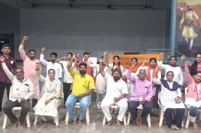 Group of activists and community members posing indoors with raised fists during a meeting linked to Maharashtra concert alcohol ban and Sunburn Festival probe