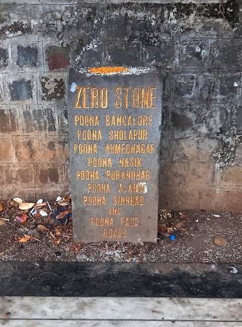 Pune Zero Stone milestone with faded lettering, stained wall and littered surroundings, showing neglect of the 150-year-old heritage landmark.
