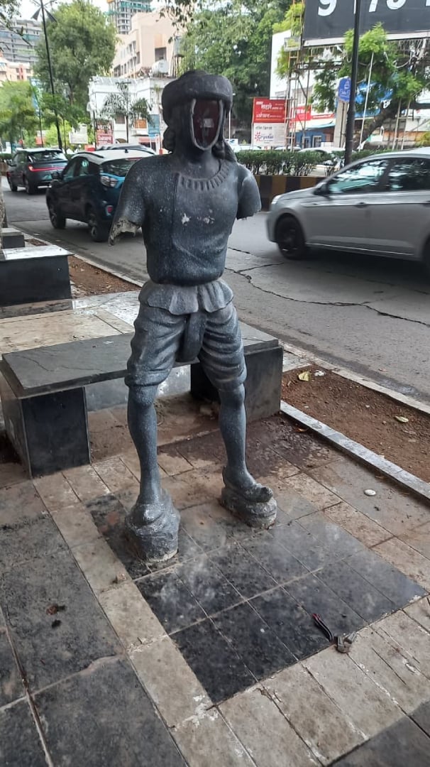 Damaged armless statue standing on a tiled footpath near Pune’s historic Zero Stone precinct, showing civic neglect, vandalism and poor heritage conservation.