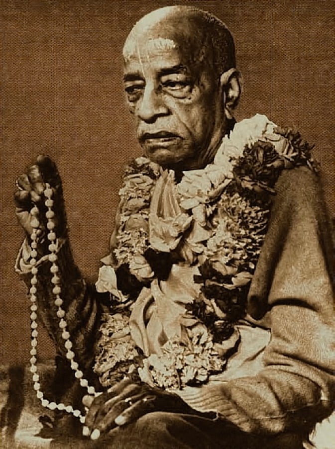 Sepia portrait of Srila Prabhupada holding japa beads and wearing flower garlands, honoring the pure devotee in Krishna consciousness.