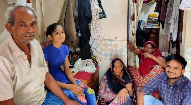 भारत के निम्न आय वर्ग का प्रतिनिधित्व करता एक परिवार, छोटे कमरे में बैठे पांच सदस्य, सीमित जगह और घरेलू सामान के बीच जीवन
