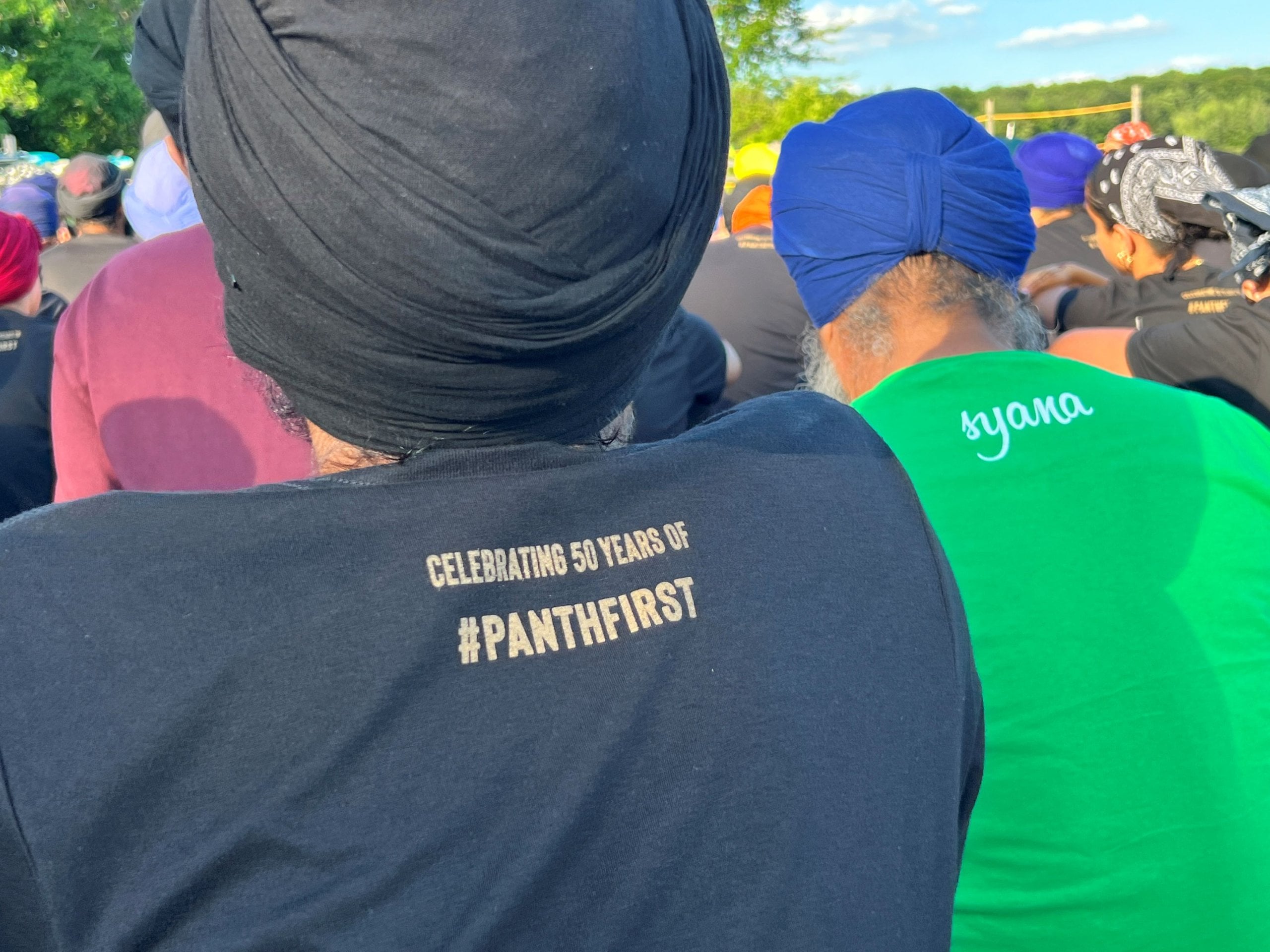 Sikh camp gathering with attendees in turbans, including a shirt reading “Celebrating 50 years of #PANTHFIRST,” honoring Gurmat camp legacy.