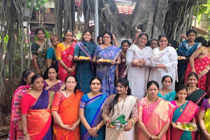Group of Indian women in colorful sarees gathered beneath a large banyan tree, holding ritual plates; related to a Solapur news report on civic and community issues.
