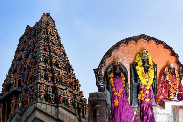 Colorful Hindu temple gopuram and three flower-adorned deities, representing Shri Ram Mandir land protection in Achalpur, Maharashtra.