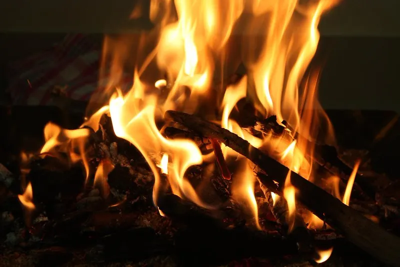 Close-up of glowing flames and burning wood, evoking Hindu ritual fire, remembrance, Dharma, and Vaikuṇṭha Samārādhana traditions in Bharat.