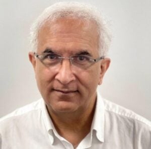 Headshot of an older Bharatiya diaspora medical speaker in glasses and a white shirt, illustrating World and Bharat heart health concerns.