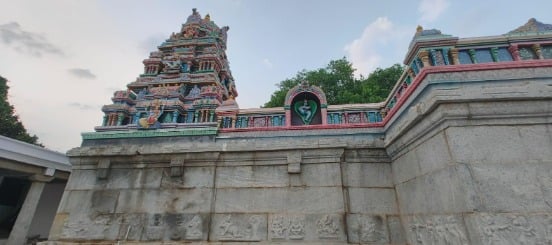 Low-angle view of the colorful gopuram and stone walls of Sri Rukmini-Satyabhama Venugopalaswamy Temple in Devanahalli Fort, Karnataka