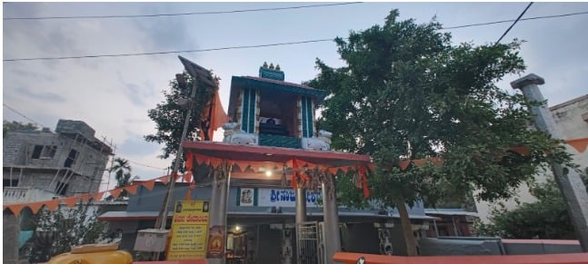 Sri Nanjundeshwara Swamy Temple entrance in Devanahalli, Karnataka, with a painted tower, orange flags and a large tree near Bengaluru.
