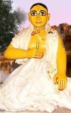 Seated devotional figure of Vakresvara Pandit in white robes with folded hand, shown in a traditional Gaudiya Vaisnava portrait style.