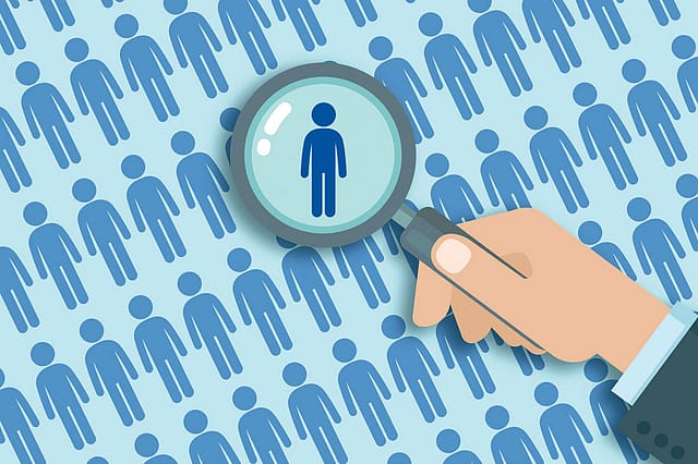 Illustration of a magnifying glass highlighting one person among many, symbolising Bharat Internal Security scrutiny of border-state demographic changes.