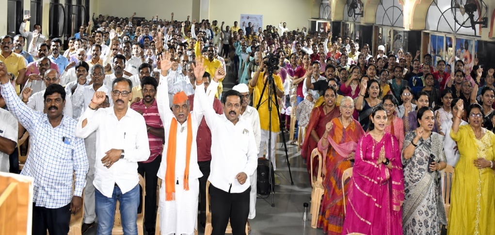 Large crowd at an HJS love jihad awareness lecture in Ichalkaranji, with attendees standing and raising hands during a pledge.