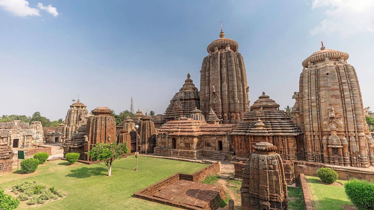 Lingaraj Temple complex in Bhubaneswar, Odisha, showing ornate Kalinga-style Hindu temple towers, shrines, lawns, and stone carvings under a clear sky.