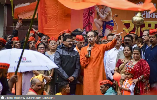 Uddhav Thackeray, in an orange kurta, speaks into a microphone and gestures to a crowd during a saffron-themed Ram Raksha Yatra gathering.
