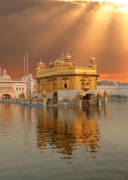 The Golden Temple, Sri Harmandir Sahib, glowing beneath sunbeams and reflected in the calm waters of the Amrit Sarovar in Amritsar.