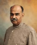 Portrait of Syama Prasad Mookerjee in a grey traditional Indian jacket against a warm, softly mottled background, reflecting his political legacy in Bharat.