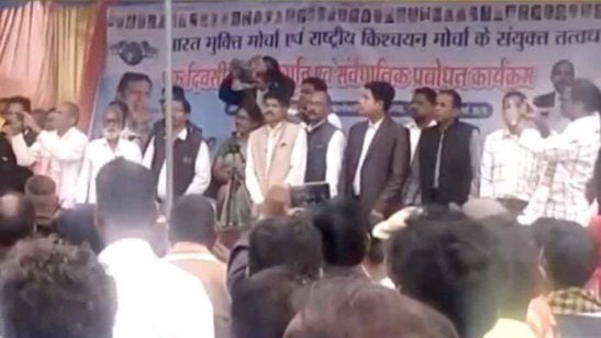 Men stand shoulder to shoulder on a stage beneath a Hindi banner as a dense audience watches, in an image linked to the Chhattisgarh ‘Hindu Is an Abuse’ case.