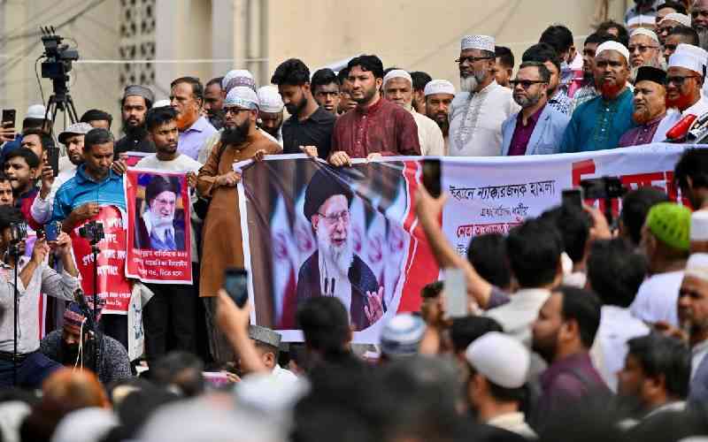 Bangladeshi demonstrators at a Dhaka rally hold banners and large portraits of Iran’s Ayatollah Ali Khamenei as a dense crowd looks on.