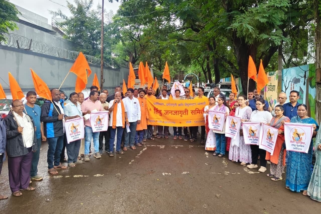 Members of Hindu Janajagruti Samiti gather on a tree-lined street with saffron flags, an orange banner and campaign placards.