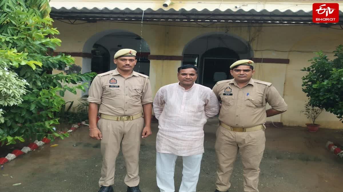 Two uniformed Uttar Pradesh police officers stand beside a man in white outside a station in Bareilly, linked to an alleged religious conversion case.