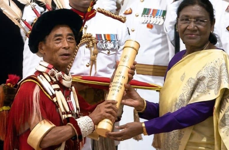 Padma Awardee Sangyusang S. Pongener, in traditional Ao Naga attire, receives an award scroll from President Droupadi Murmu at a formal ceremony.