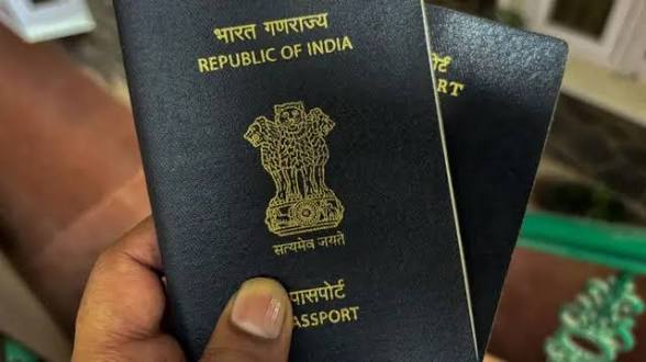 हाथ में पकड़े दो गहरे नीले भारतीय पासपोर्ट का क्लोज-अप, जिन पर भारत गणराज्य, अशोक स्तंभ और ‘पासपोर्ट’ सुनहरे अक्षरों में अंकित हैं।