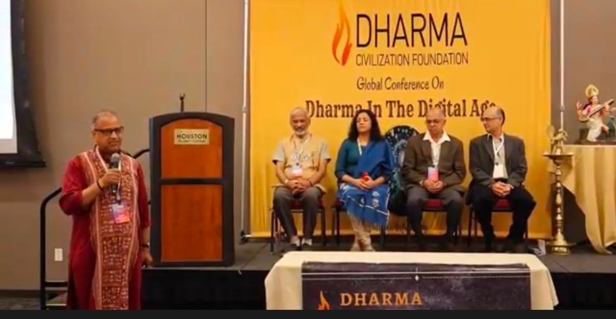 Speaker addresses four seated panelists beneath a Dharma Civilization Foundation conference banner.