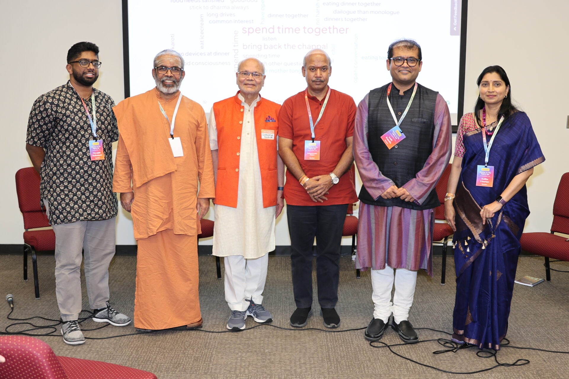 Six conference attendees stand together in front of a projected word cloud.