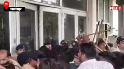 A tightly packed crowd, including people in dark caps and khaki clothing, gathers outside glass doors.