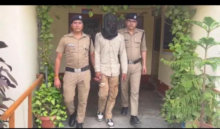 Two uniformed officers walk beside a man with a black hood covering his head outside a building.